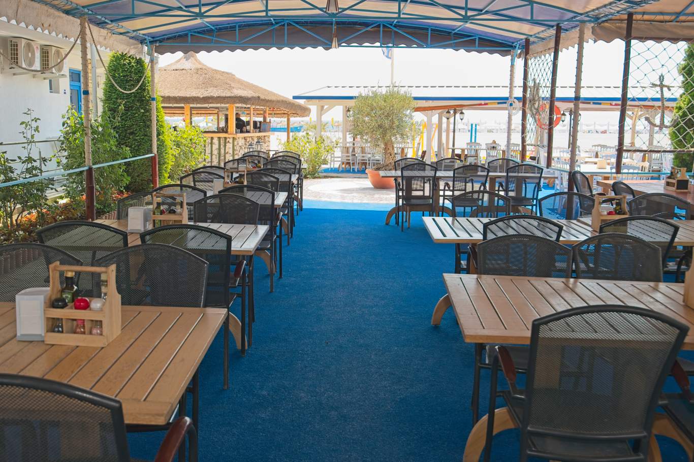 Terasă spațioasă acoperită cu vedere către bar și plajă