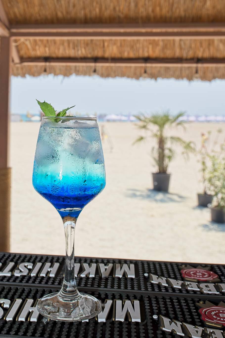 Cocktail albastru cu umbrelă decorativă pe tejgheaua barului exterior
