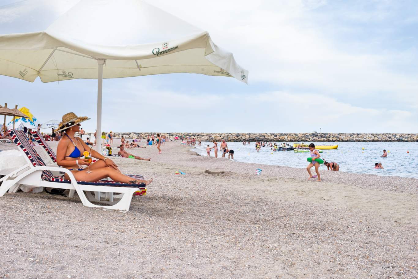 Turist relaxat pe șezlong cu umbreluță albă pe plaja Hotel Hercules în zi însorită