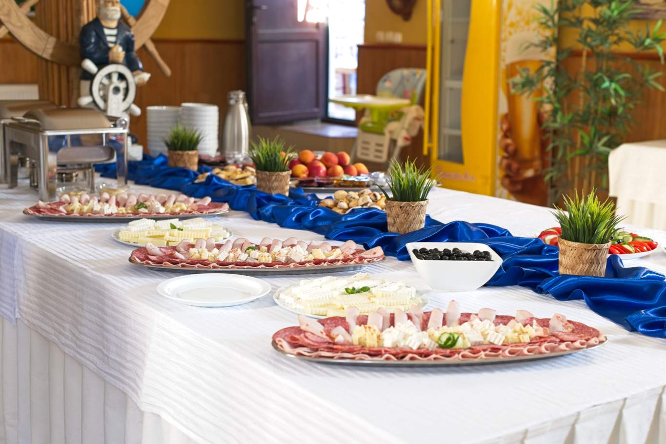 Masă lungă cu bufet de aperitive, salate și preparate reci pentru micul dejun