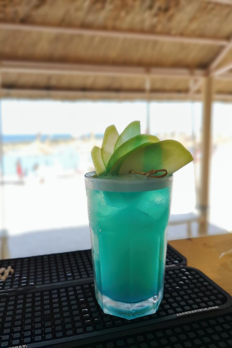 Pahar înalt cu mojito verde cu frunze de mentă proaspătă și felii de lime
