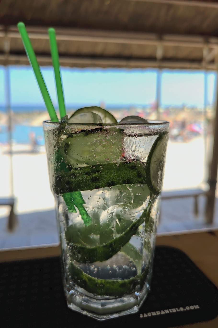 Băutură răcoritoare verde-aqua cu pai, servită lângă plajă