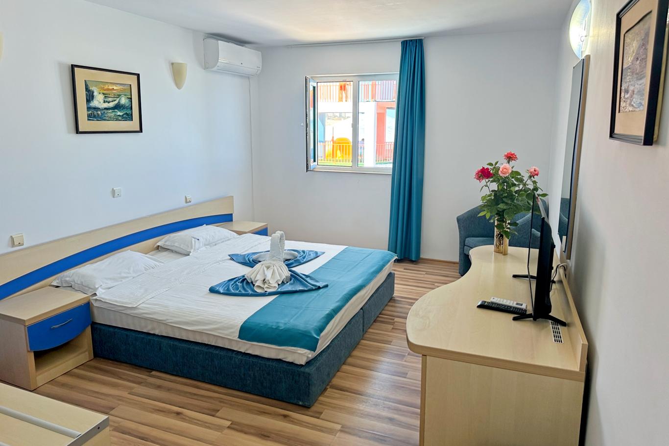 Cameră Hotel Hercules cu pat dublu, lenjerie albă și turcoaz, tablou decorativ și parchet