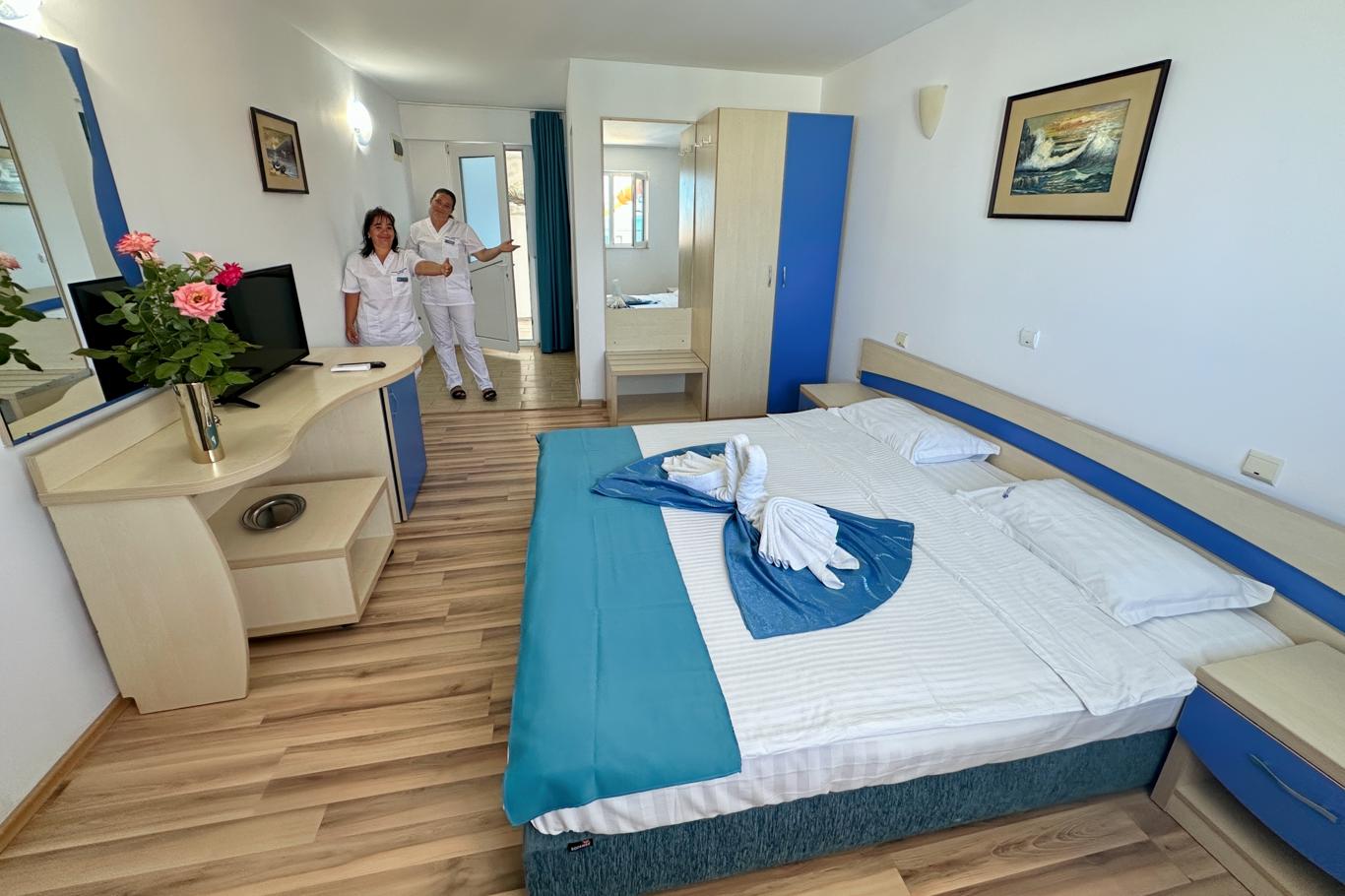 Cameră la Hotel Hercules cu personal în uniformă albă pregătind camera pentru oaspeți