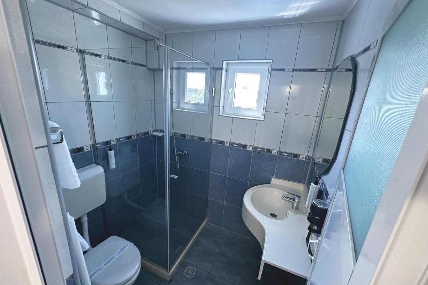 Baie cu cabină de duș din sticlă, gresie modernă închisă și dotări complete