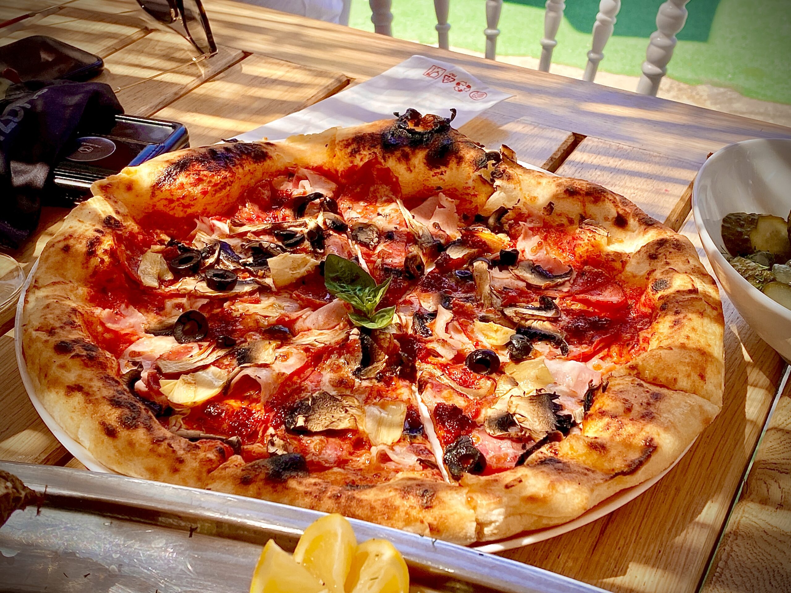 Pizza mare, rotundă, cu topping din roșii, mozarella și ierburi aromatice, pe blat de lemn
