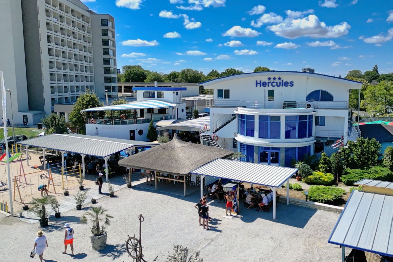 Vedere aeriană a zonei de promenadă Hotel Hercules cu terase, umbrar și turiști